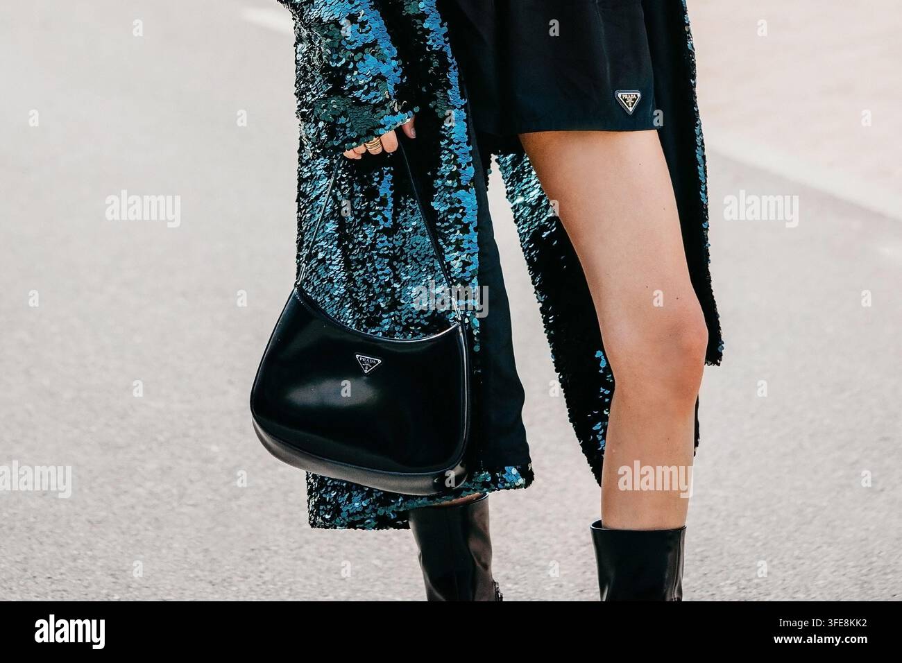 Milano, Italia - 24 settembre 2026: Donna con borsa a tracolla Prada Cleo nera e cappotto con paillettes Foto Stock
