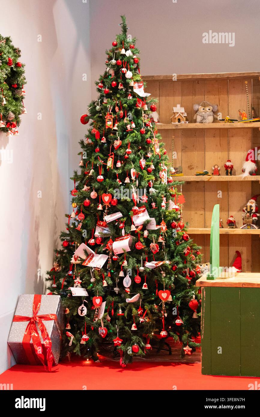 Albero di Natale con ornamenti rossi e bianchi e decorazioni interne festive Foto Stock