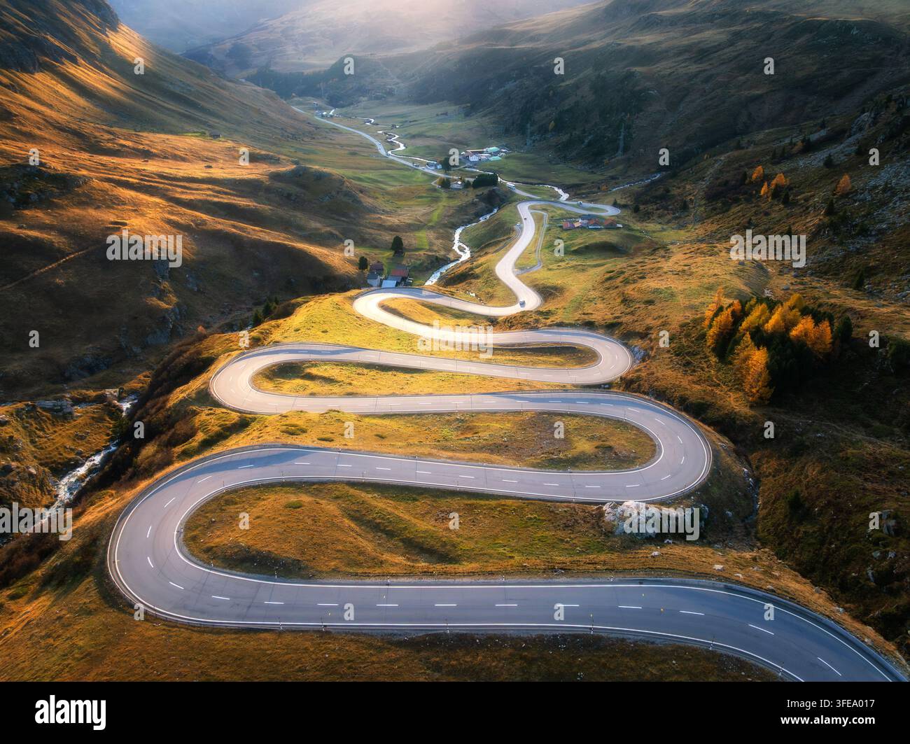 Vista aerea della tortuosa strada di montagna, fiume nella valle alpina Foto Stock