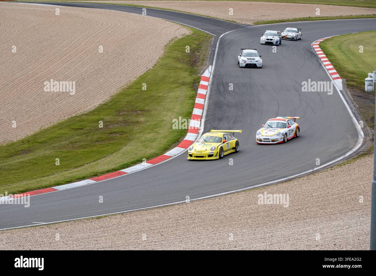 Le auto da corsa Porsche GT si sfidano in una curva ampia durante un evento competitivo di sport motoristico su un circuito professionale. Foto Stock