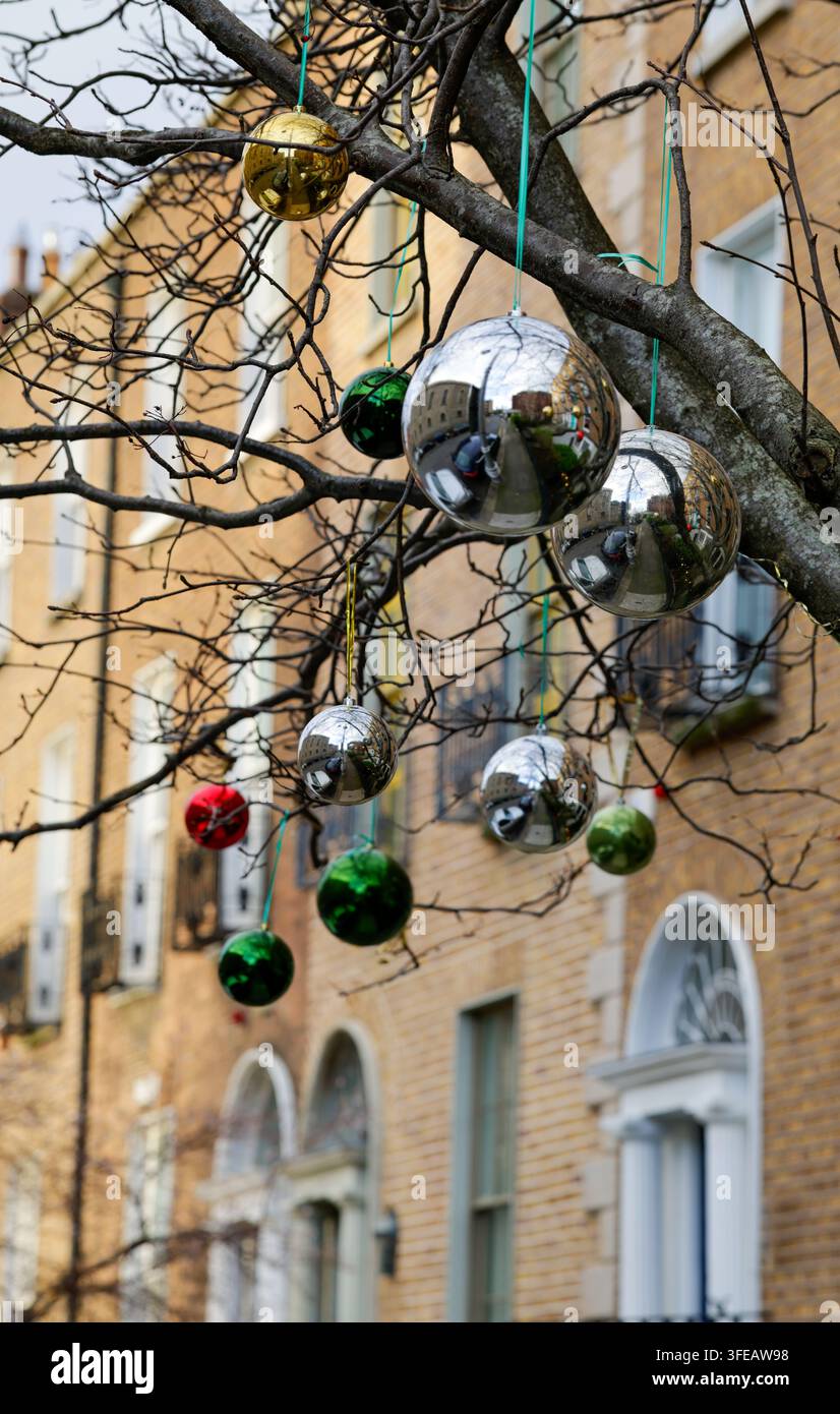 Palle decorative appese ai rami di un albero davanti alla terrazza di case georgiane nella città di Dublino. Decorazioni esterne per il Natale. Irlanda Foto Stock