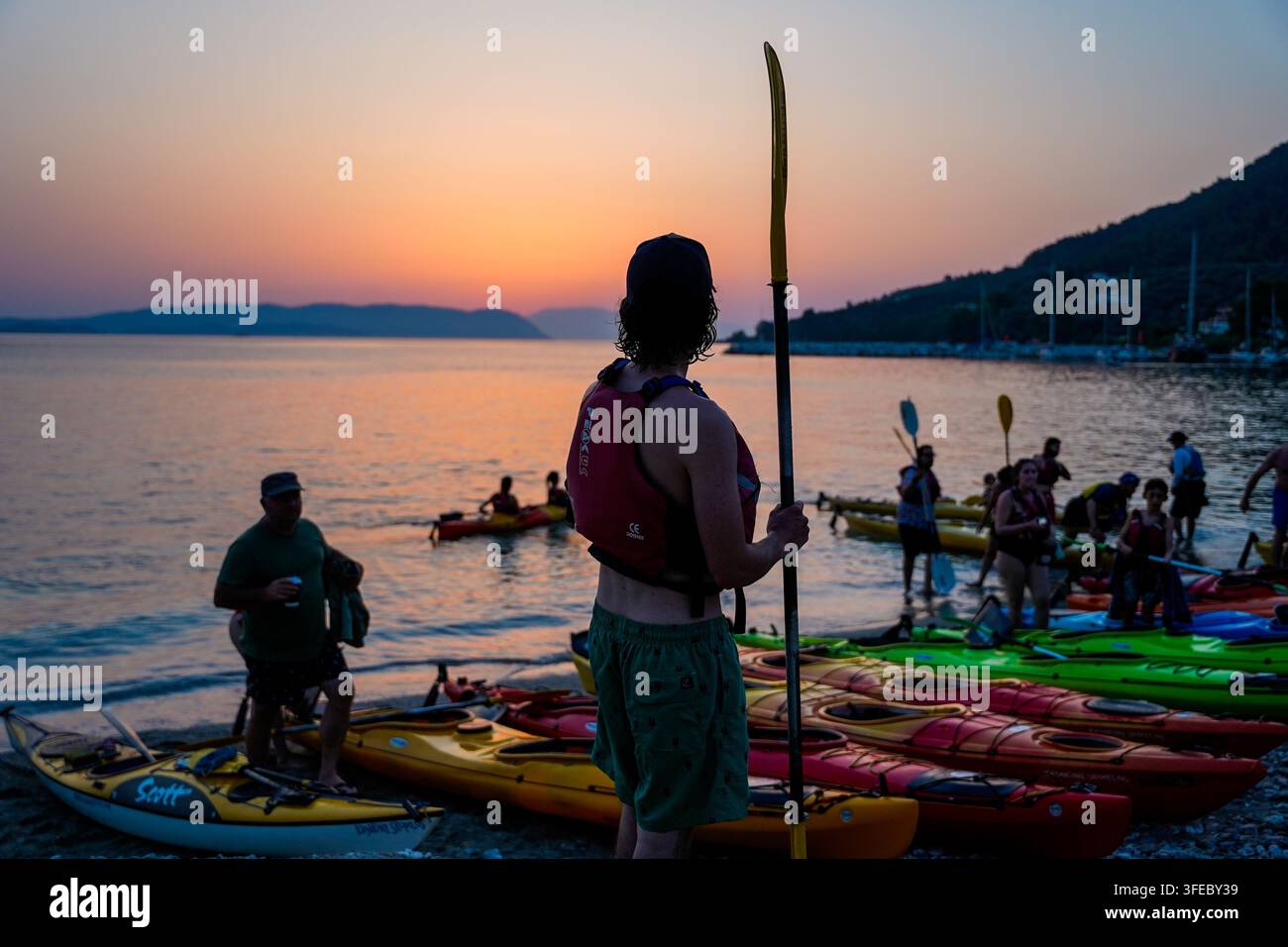 Kayaker che osserva il tramonto prima di un'escursione di pagaia di gruppo Foto Stock