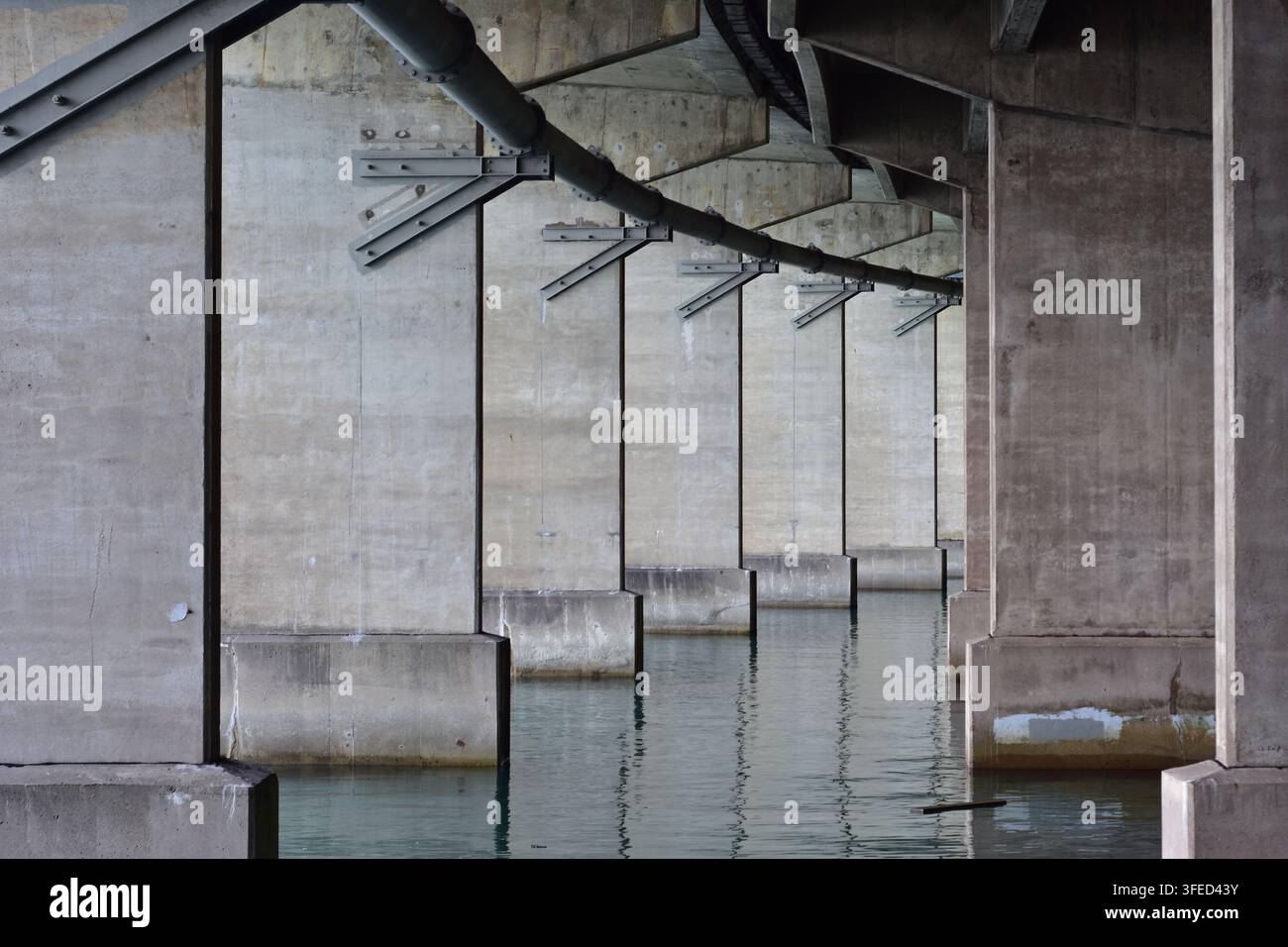 Piloni di sostegno in cemento e tubi di servizio sotto il ponte del porto di Auckland ad Auckland, Nuova Zelanda. Foto Stock