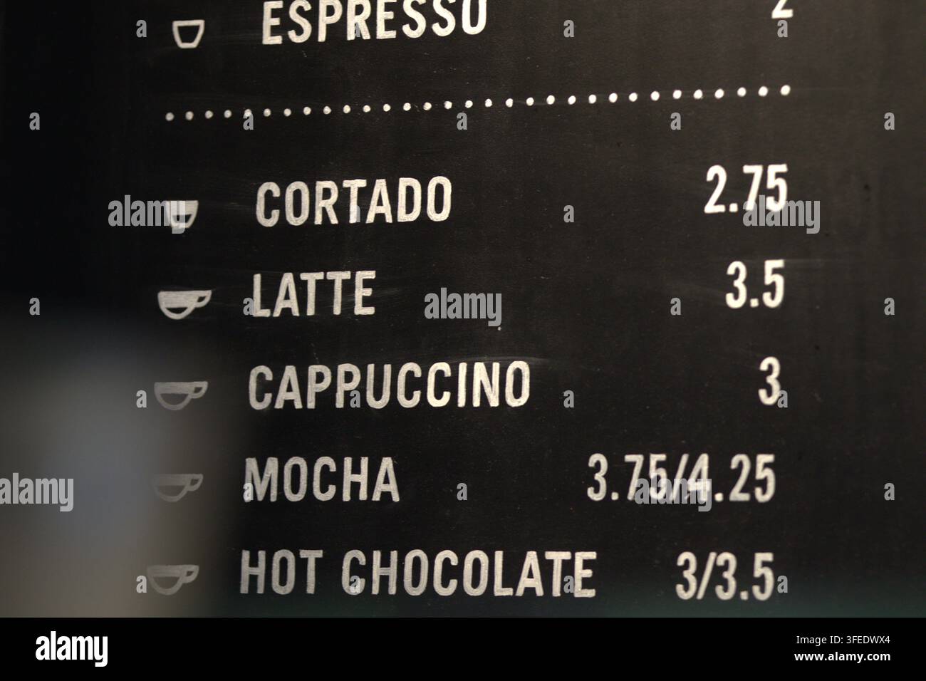 Prima piano di una moderna lavagna del menu di un bar con bevande espresso, prezzi e piccole icone di tazze di caffè. Foto Stock