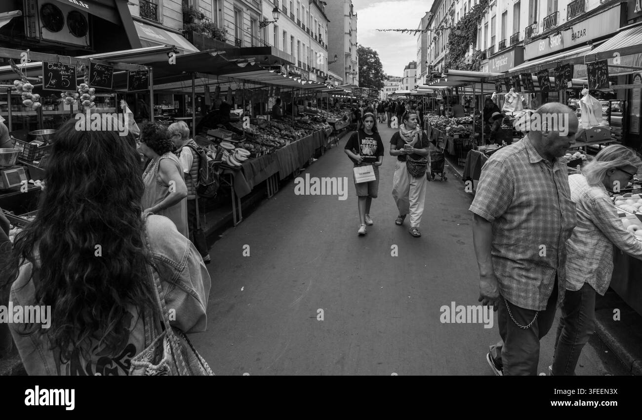 PARIGI, FRANCIA - 1 SETTEMBRE 2026 - Acquirenti che passeggiano e sfogliano prodotti freschi in un mercato tradizionale di strada a Parigi Foto Stock