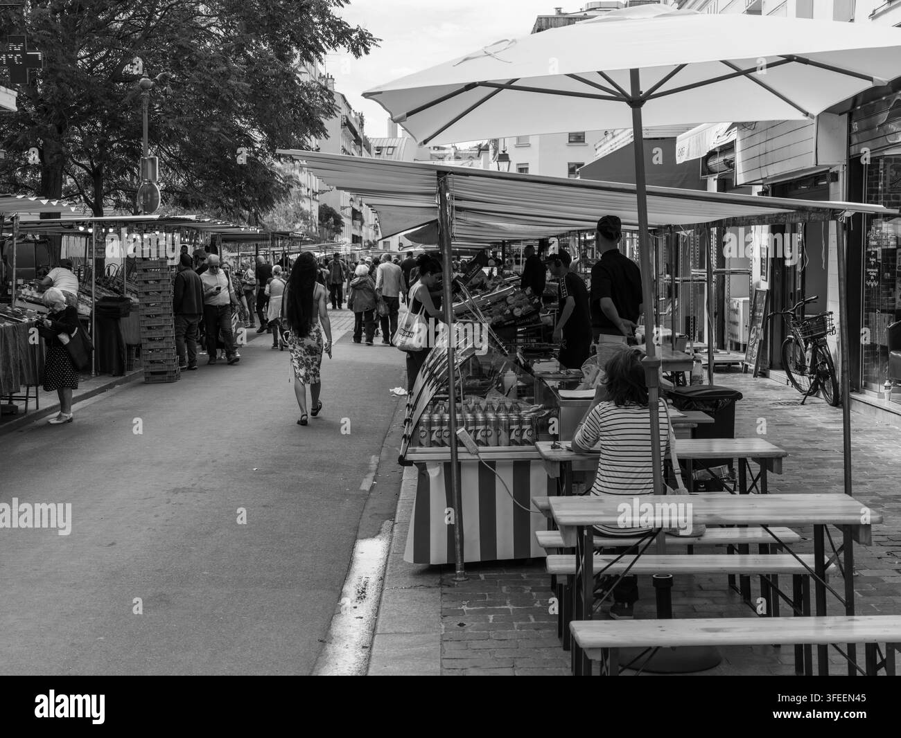 PARIGI, FRANCIA - 1 SETTEMBRE 2026 - Gli acquirenti curiosano tra le bancarelle e passeggiano lungo una vivace strada del mercato all'aperto Foto Stock