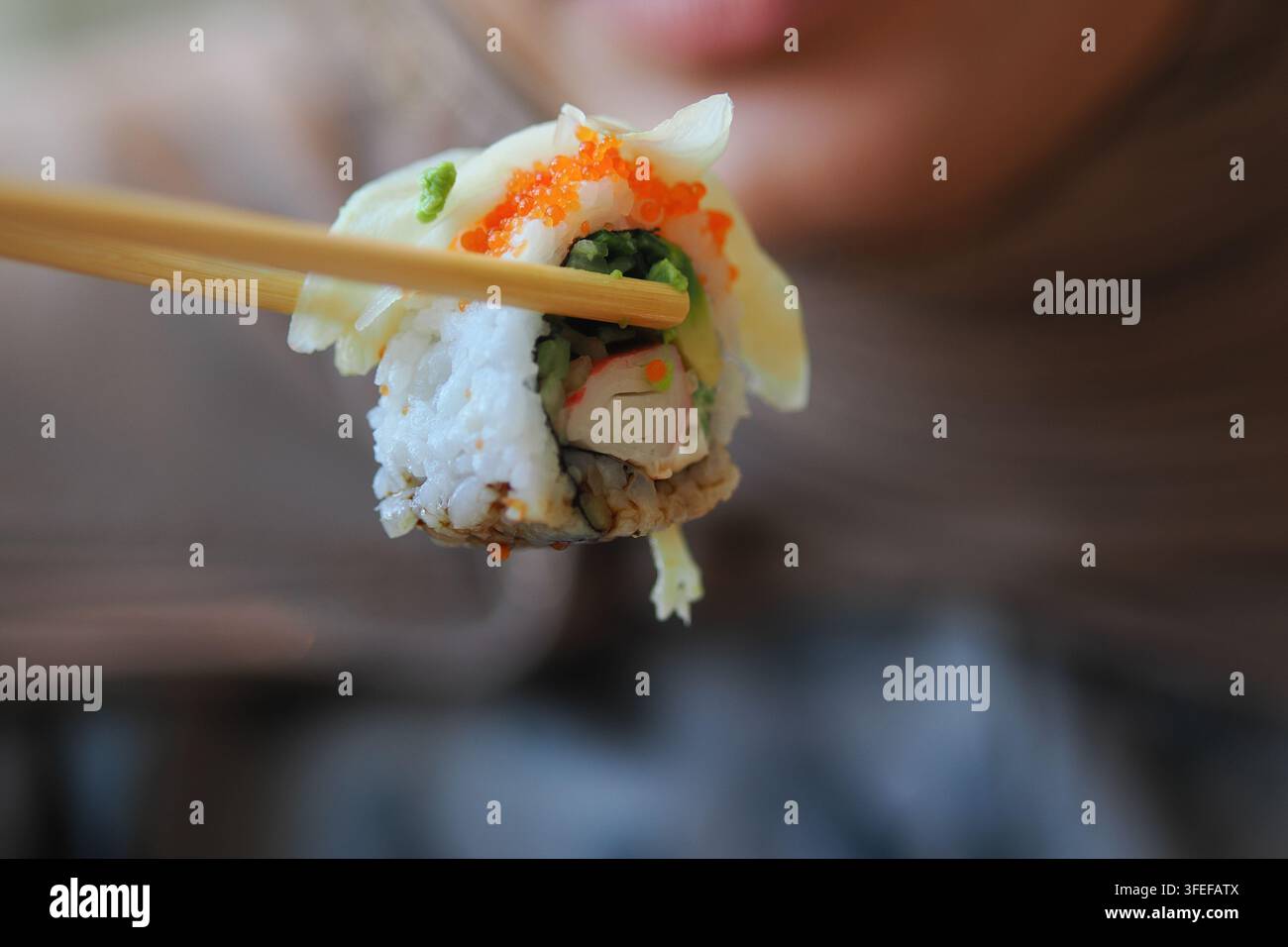 Mangiare sushi con bacchette in un ambiente informale Foto Stock