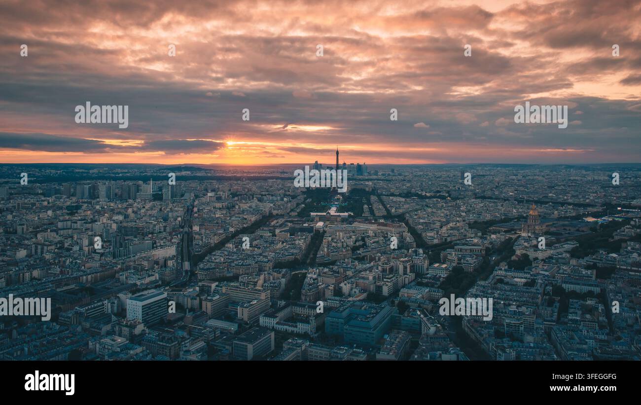 Vista aerea di Parigi al tramonto, catturata dalla Tour Montparnasse, con la Torre Eiffel che si erge sopra lo skyline della città e i grattacieli di La Défense Foto Stock