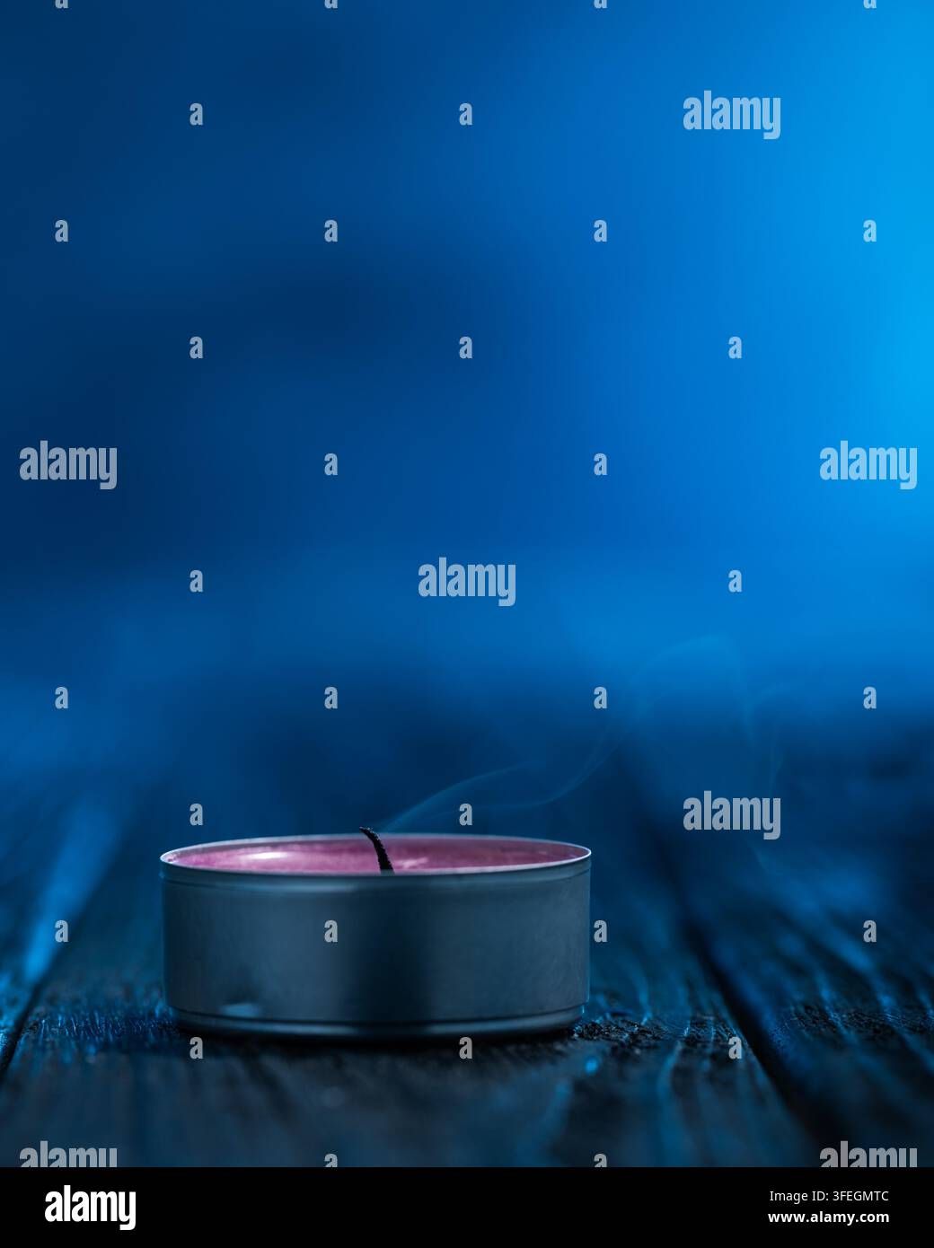 Candela spenta con fumo delicatamente arricciato su una superficie di legno scuro e sfondo blu atmosferico. Composizione autunnale con generoso co Foto Stock