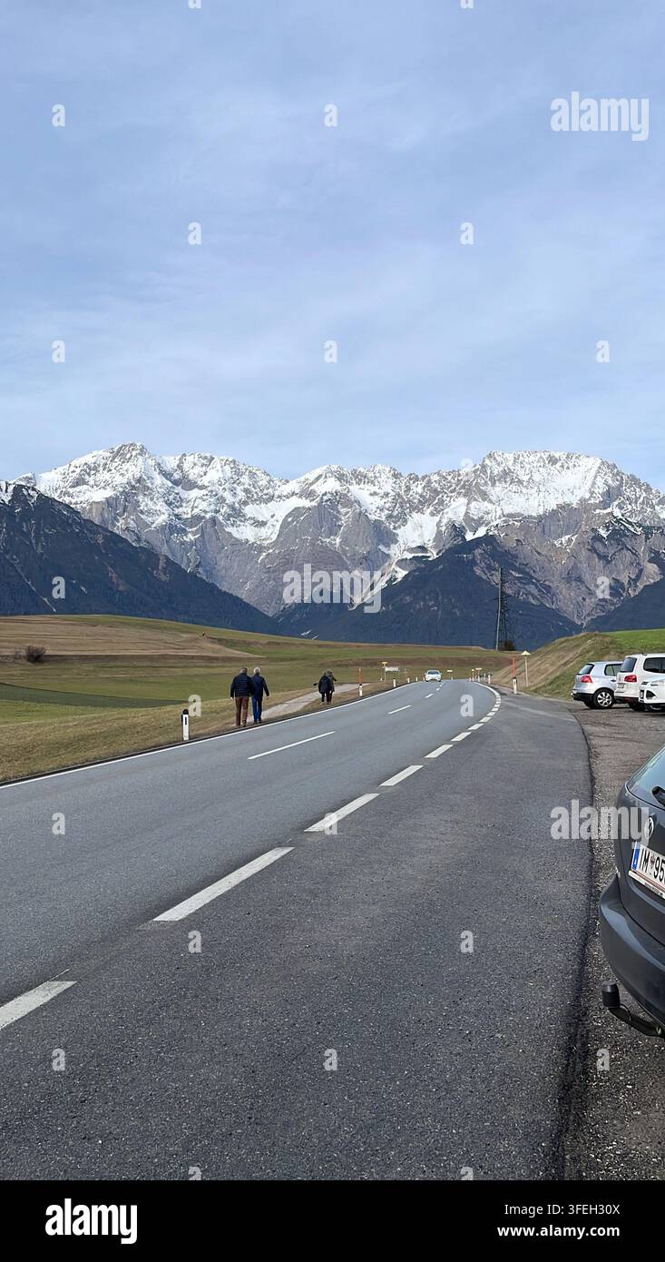 Strada panoramica attraverso l'Austria circondata da foreste sempre verdi e montagne alpine innevate sotto la luce intensa del sole. - Immagine stock catturata con smartphone
