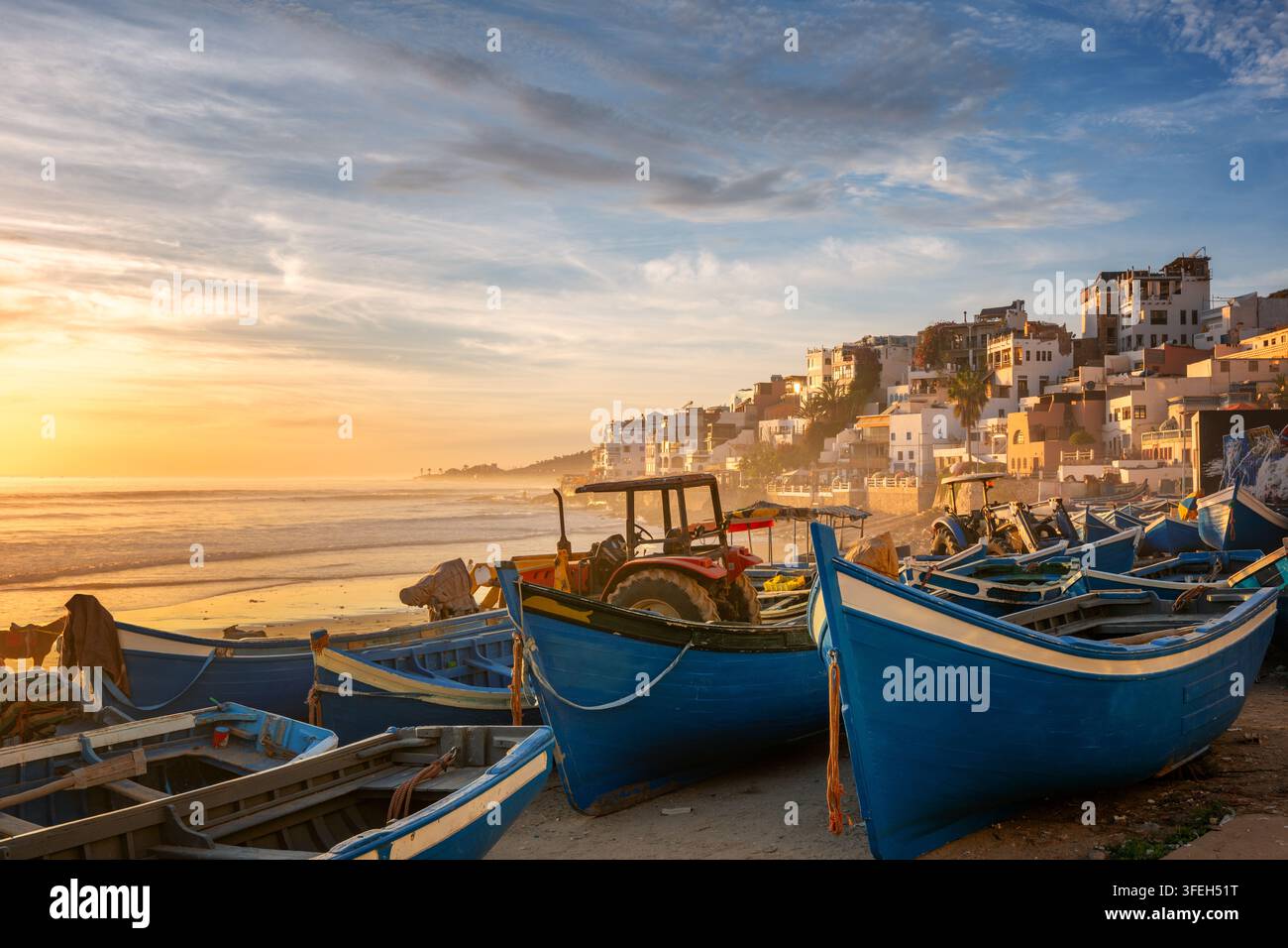 Barche da pesca blu su una spiaggia marocchina al tramonto Foto Stock