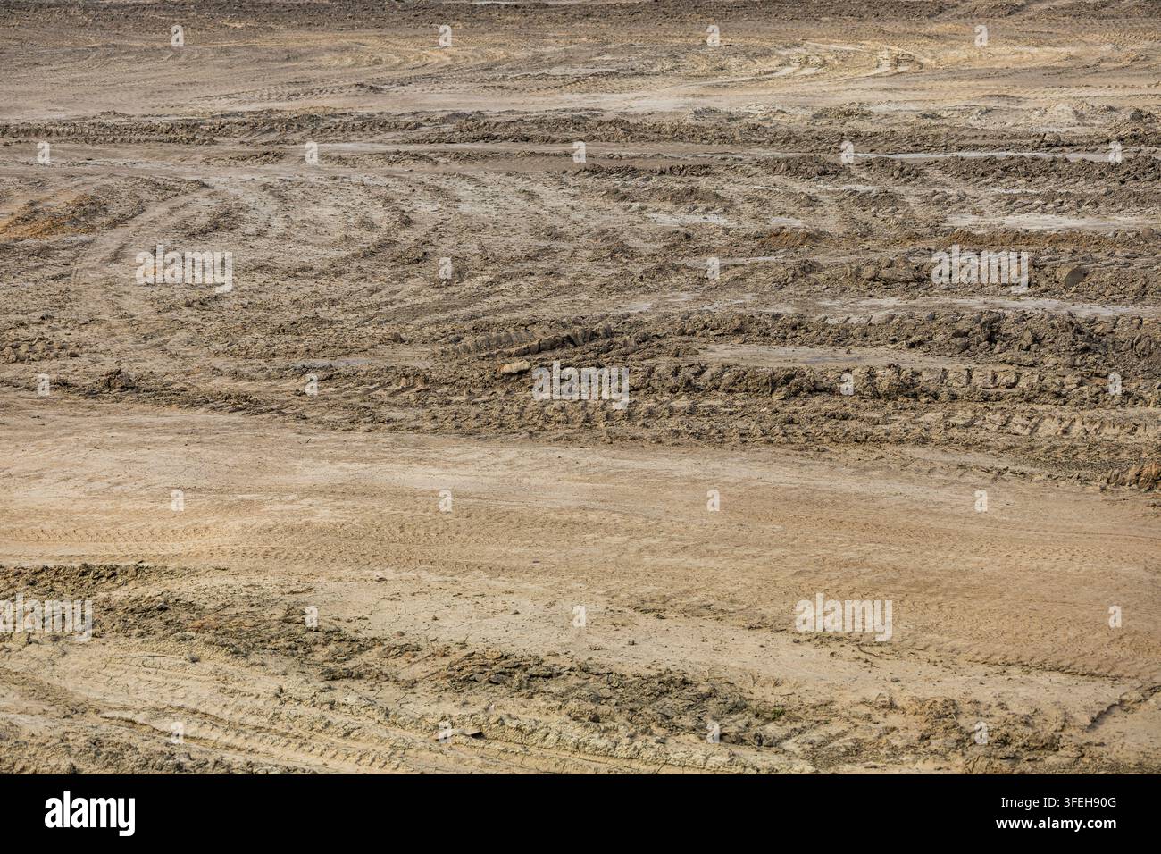 Binari curvi e texture di sabbia compattata che coprono il terreno aperto su un cantiere di movimento terra commerciale. Foto Stock