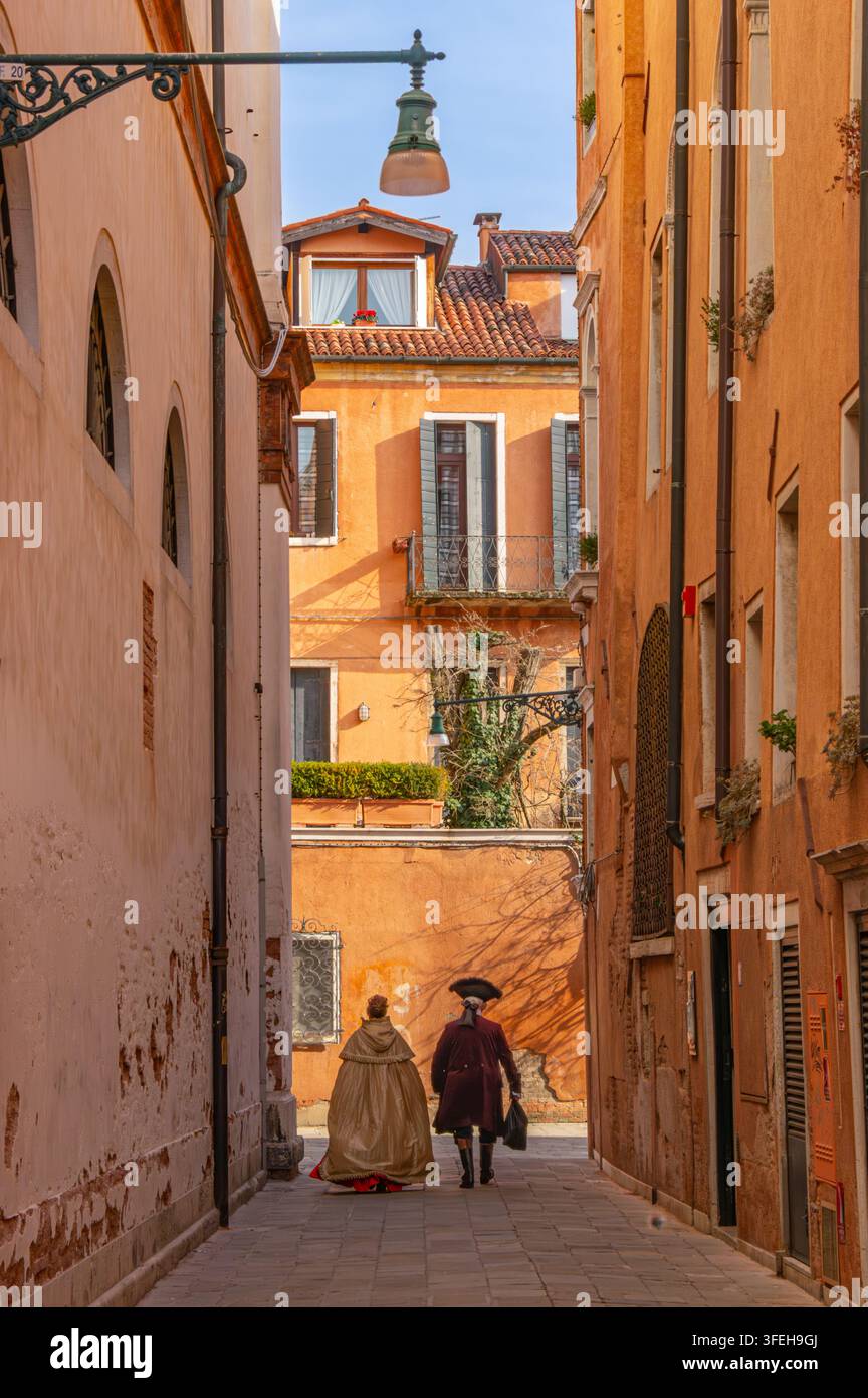 Coppia in costumi storici che cammina lungo un vicolo di Venezia Foto Stock