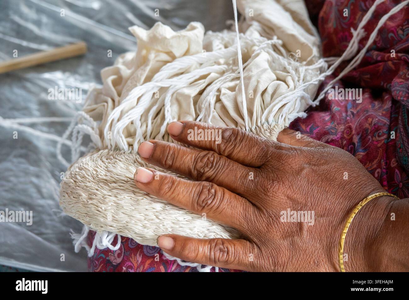 Artigiano che prepara un fascio di tessuto tinto a nodi shibori presso Living Blue, Divisione Rangpur, Goalpara, Bangladesh Foto Stock