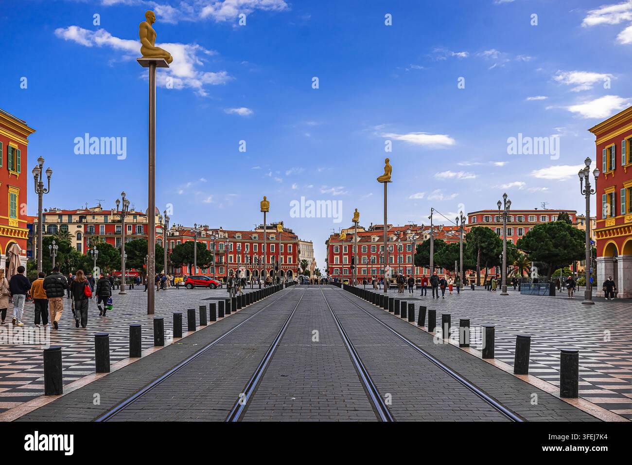 I binari del tram e le statue della "Conversazione" attirano lo sguardo verso la Place Masséna di Nizza sullo sfondo. Foto Stock