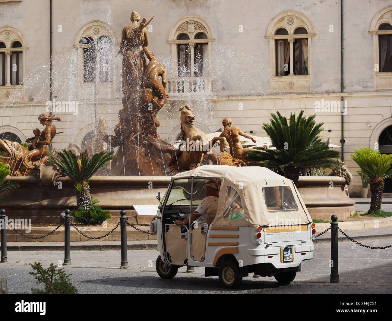 Tipico taxi turistico italiano a tre ruote Piaggio in attesa di clienti davanti a una fontana barocca a Ortygia, Siracusa, Sicilia, Italia. Foto Stock