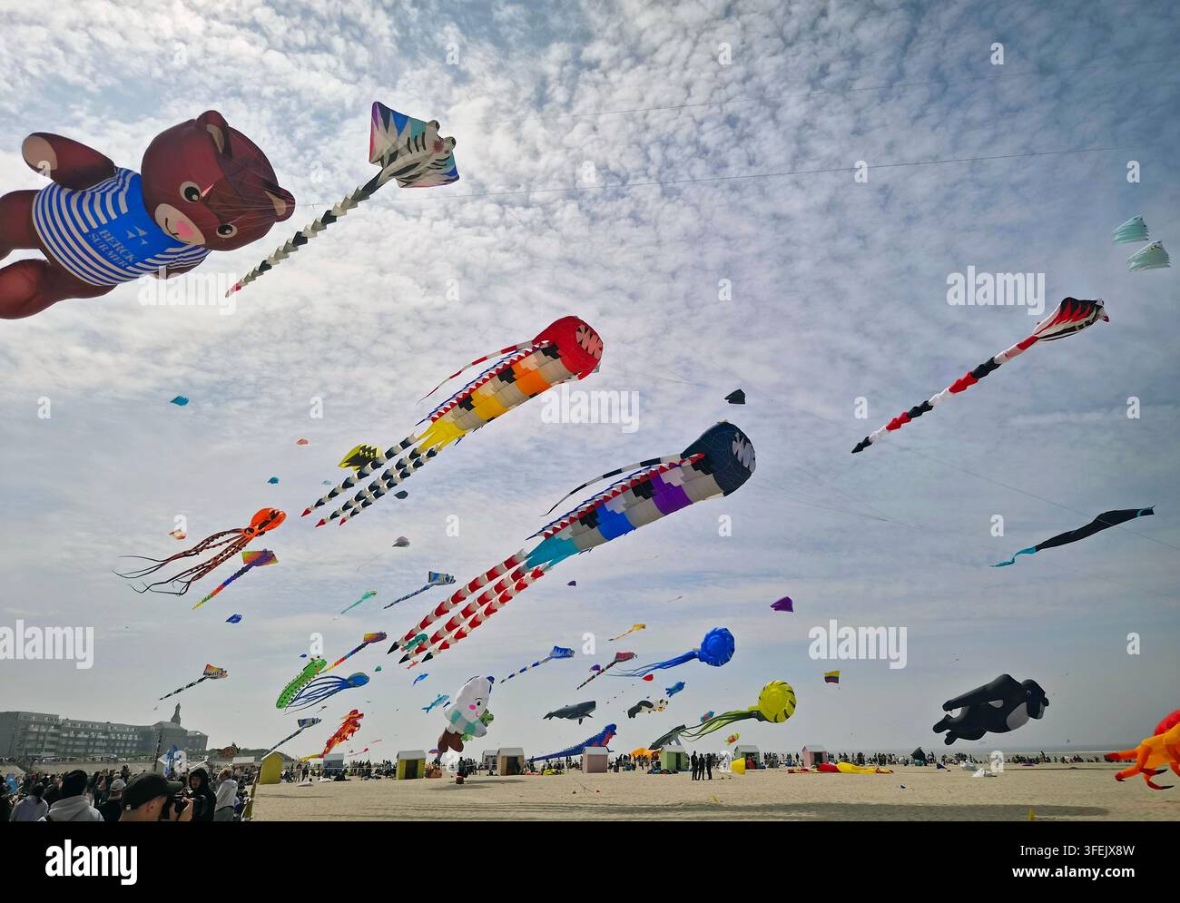 Berck-sur-Mer, Francia – 26 aprile 2026: enormi aquiloni colorati volano sopra una spiaggia sabbiosa affollata durante il Festival Internazionale degli Aquiloni. Le persone si radunano su Foto Stock