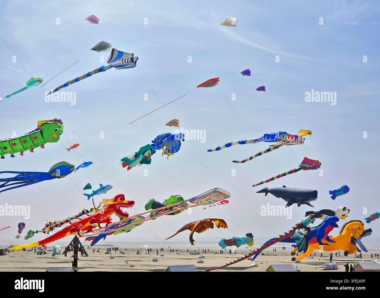 Berck-sur-Mer, Francia – 26 aprile 2026: enormi aquiloni colorati volano sopra una spiaggia sabbiosa affollata durante il Festival Internazionale degli Aquiloni. Le persone si radunano su Foto Stock