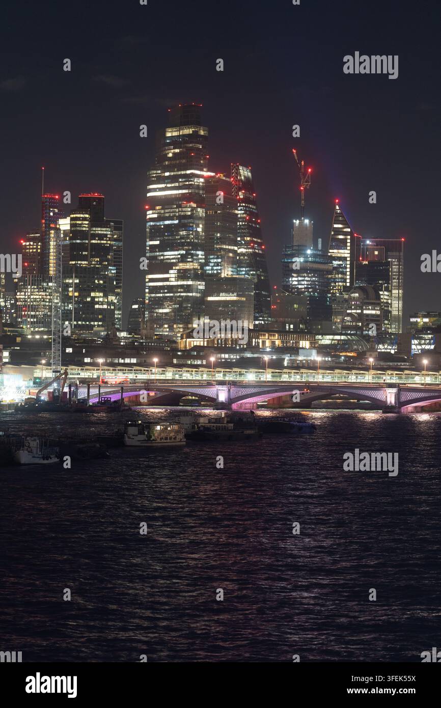 Di notte, i grattacieli illuminati si ergono sulla Tamisa, mettendo in mostra il centro finanziario della City di Londra e il ponte di Southwark. Foto Stock