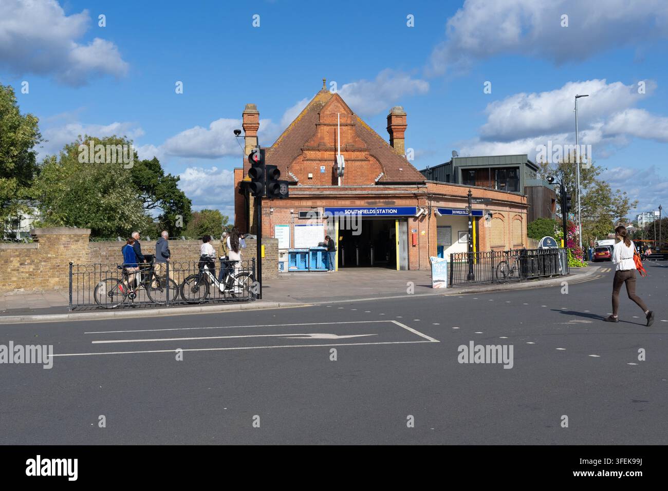 I pendolari camminano e pedalano davanti alla stazione della metropolitana di Londra Southfields a Wandsworth per accedere ai trasporti pubblici. Foto Stock