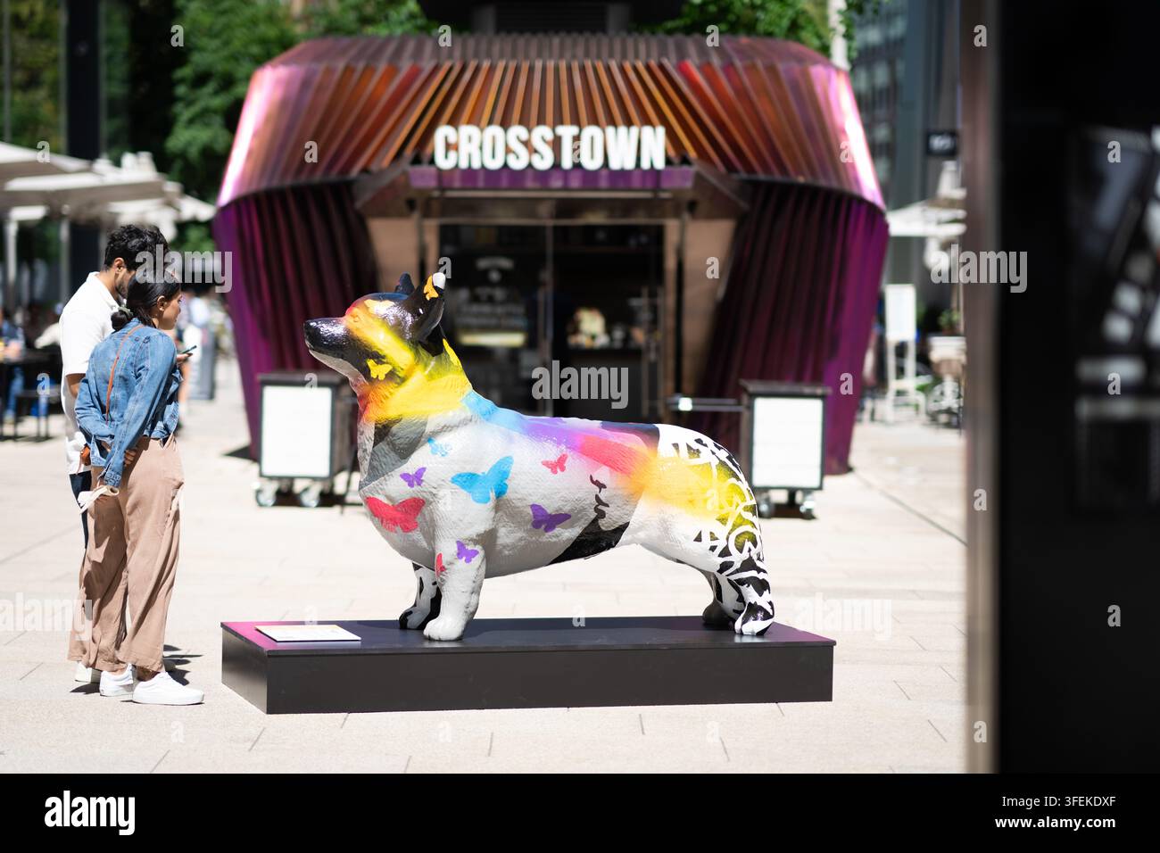I visitatori osservano un corgi dipinto fuori da Crosstown a Nova South per il Platinum Jubilee Corgi Trail della Victoria BID a Londra. Foto Stock