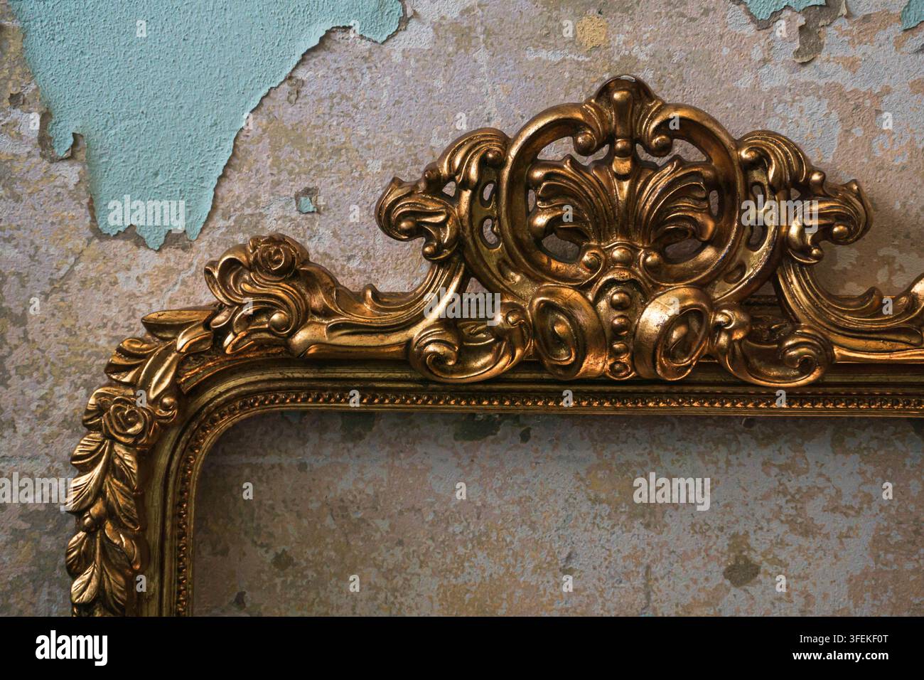 Prima vista di una cornice dorata in stile antico ornata con decorazioni barocche decorative su uno sfondo di muro texturizzato invecchiato. Foto Stock