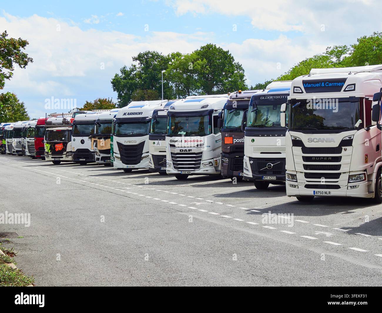 Filiera di camion merci parcheggiati a una stazione di servizio autostradale con una grande flotta di trasporto Foto Stock