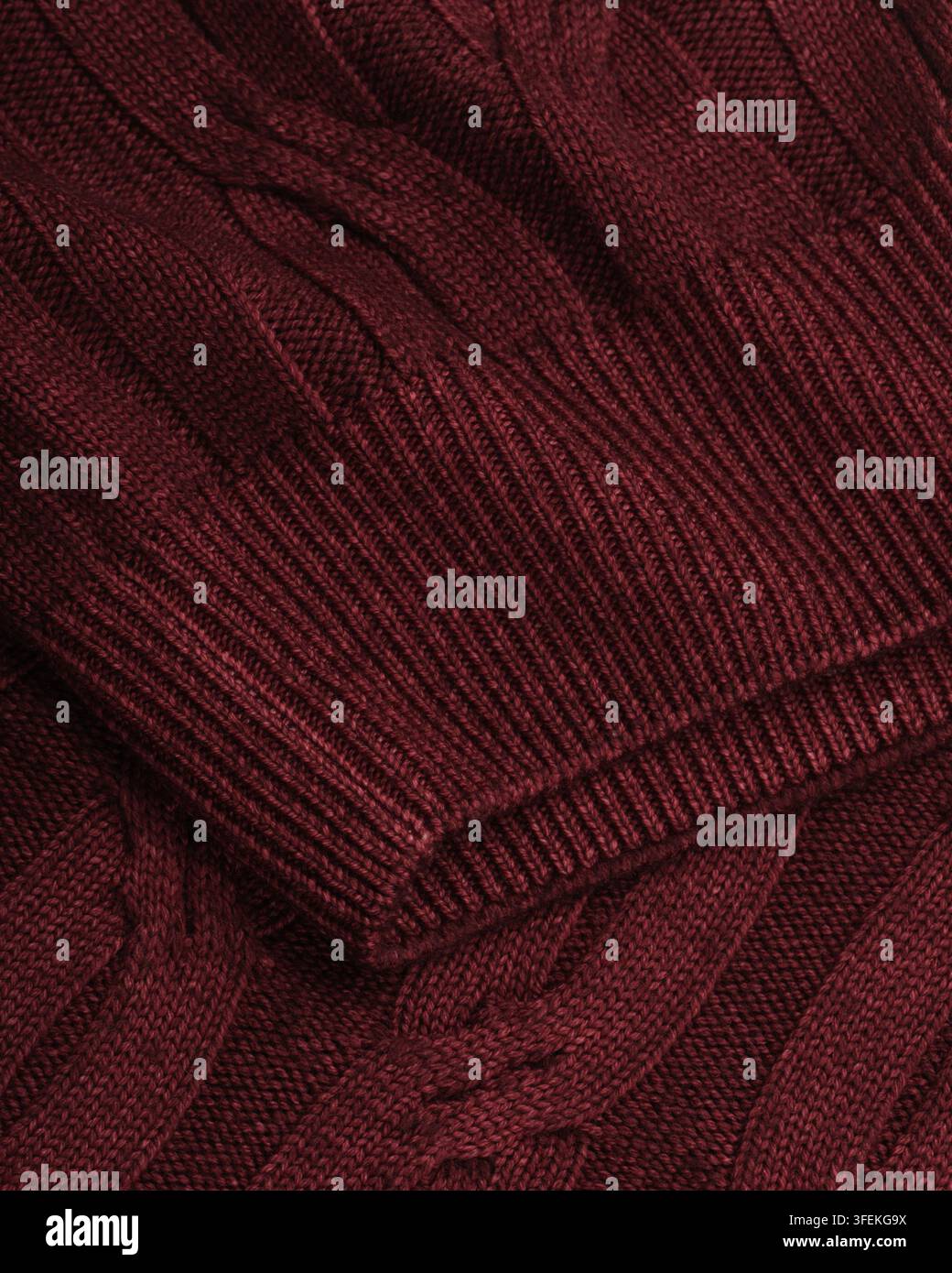 Close-up dell'orlo a costine e della texture a maglia intrecciata di un maglione bordeaux fotografato in studio per un catalogo di abbigliamento e un negozio online. Foto Stock