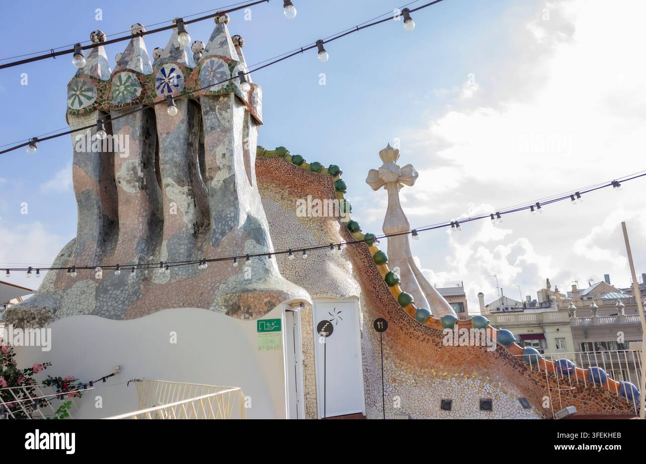 il tetto rivestito di piastrelle a mosaico e il camino a croce a quattro braccia sulla terrazza del tetto di Casa Batlló progettata da Antoni Gaudí a Barcellona Foto Stock