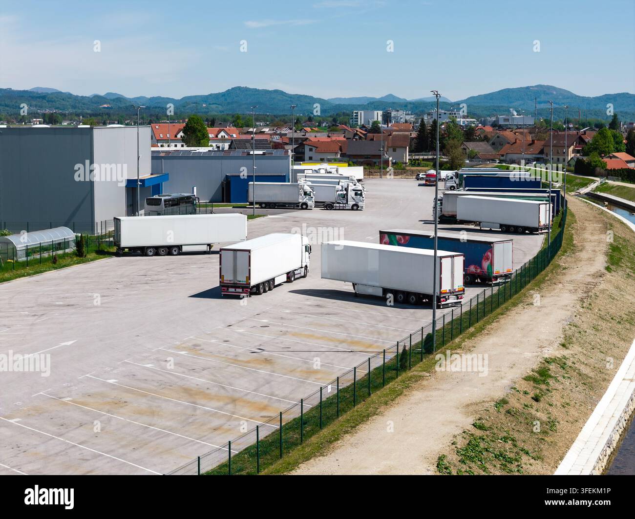 Vista aerea che mostra camion parcheggiati in un centro logistico di un terminal di carico in condizioni meteorologiche limpide. Il carico è preparato per il trasporto. Foto Stock