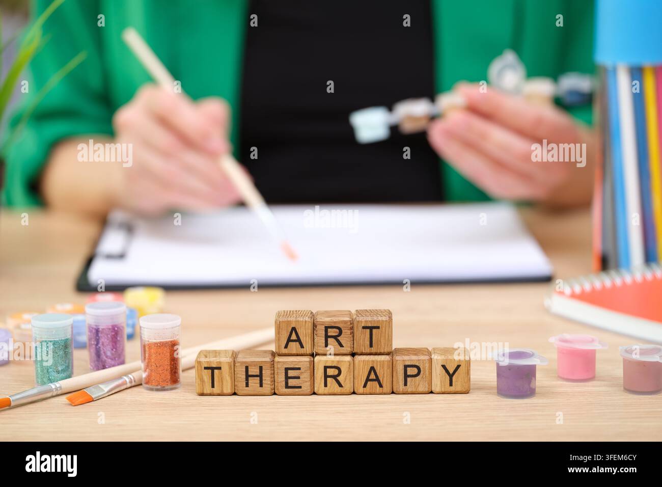 Le espressioni creative fioriscono durante le sessioni di arte-terapia in una stanza luminosa e accogliente piena di materiali vivaci Foto Stock