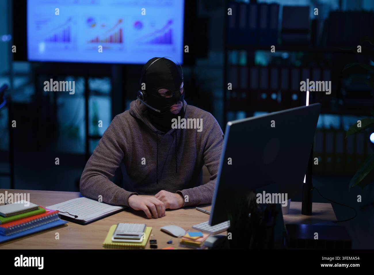 Frode con maschera e auricolari che hackera l'accesso ai conti personali Foto Stock
