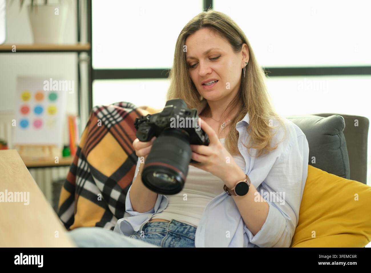 Fotografa donna controlla le impostazioni della macchina fotografica mentre si rilassa in ufficio Foto Stock