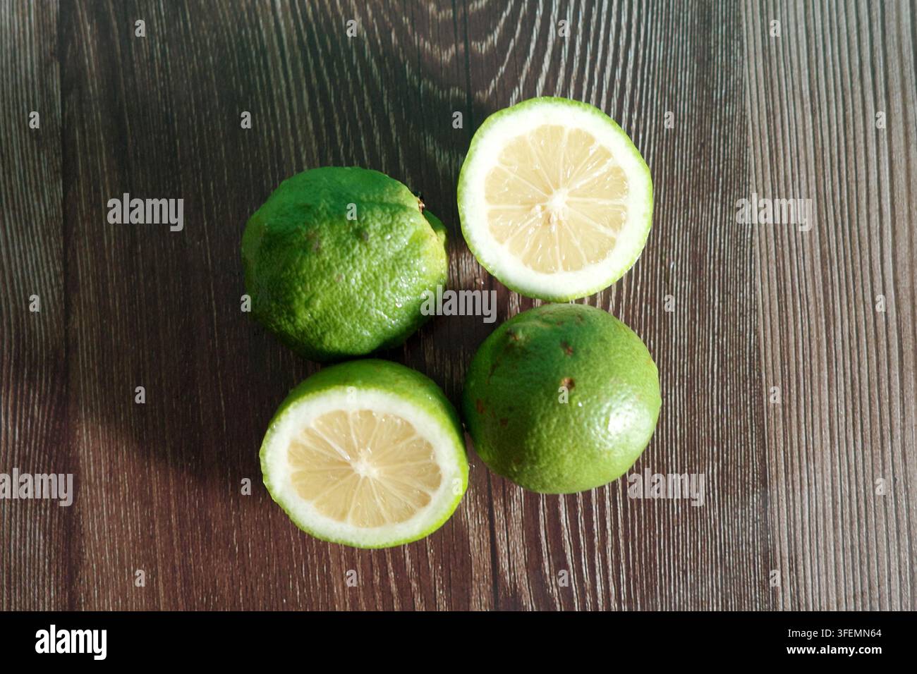 Limoni verdi freschi su uno sfondo di legno scuro Foto Stock
