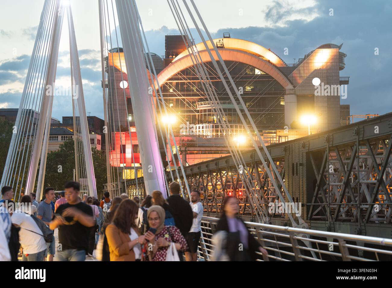 I pedoni attraversano i Golden Jubilee Bridges di Londra presso il Hungerford Bridge al crepuscolo, pendolarizzando o esplorando vicino alla Stazione di Charing Cross. Foto Stock