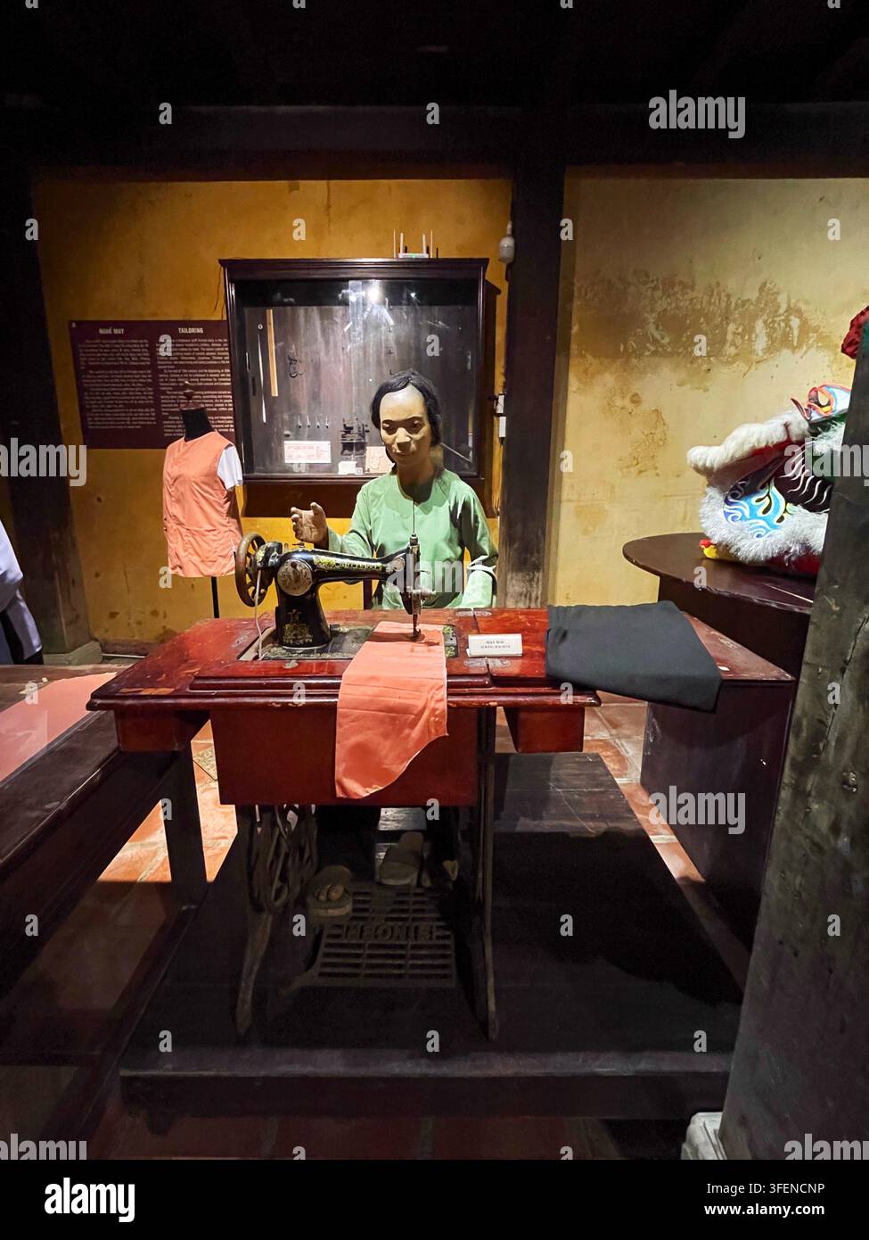 Esposizione di sartoria tradizionale con un manichino, tessuti e una macchina da cucire vintage all'interno del Museo della Pesca e delle Barche a Hoi An, 2 aprile 2026. Foto Stock