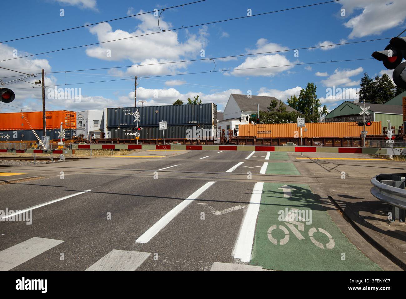 Un treno merci che si muove lentamente si ferma causando code per auto, ciclisti e pedoni in una giornata di sole a Portland, Oregon Foto Stock