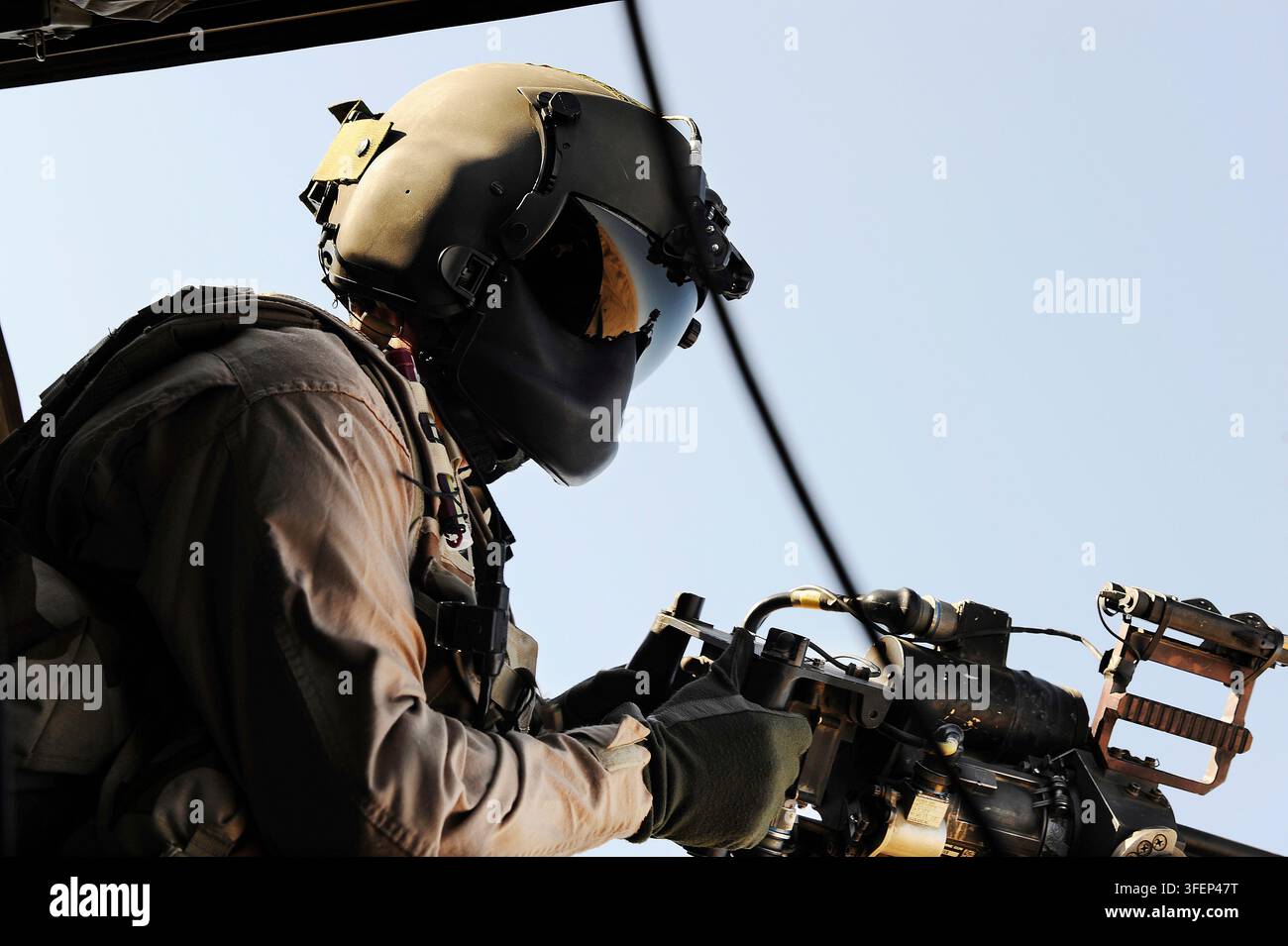 Mitragliere di elicottero che mira una mitragliatrice durante una missione di combattimento aereo. Foto Stock