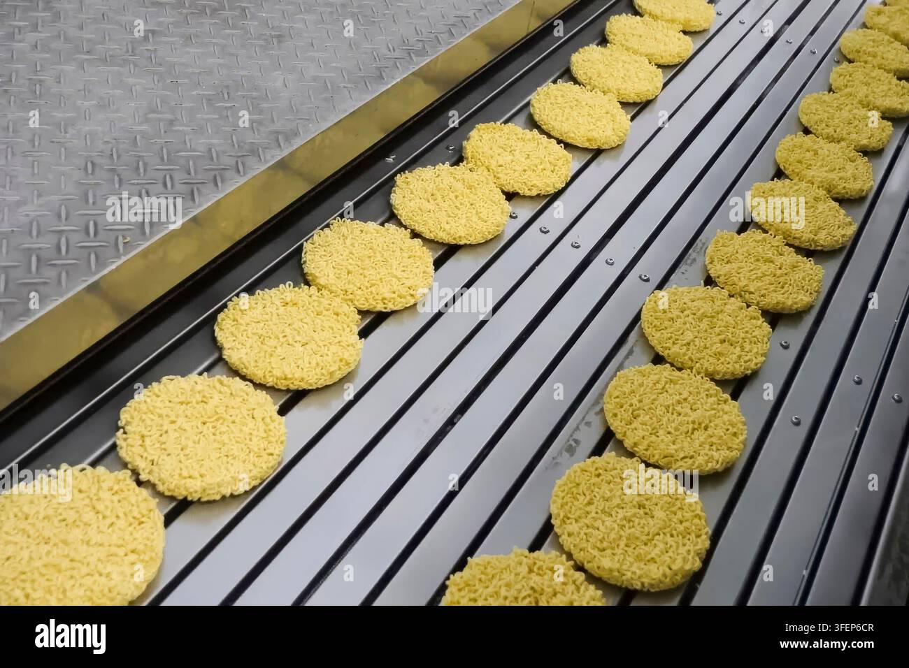 Linea di produzione istantanea di spaghetti. porzioni di spaghetti sul trasportatore, industria alimentare di massa. Foto Stock
