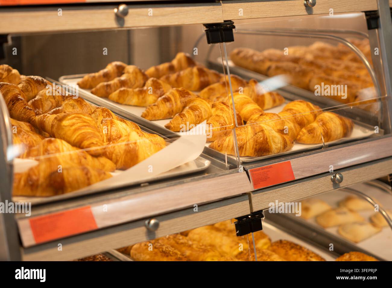 Croissant appena sfornati in attesa dei clienti in una vetrina di vetro in una panetteria Foto Stock