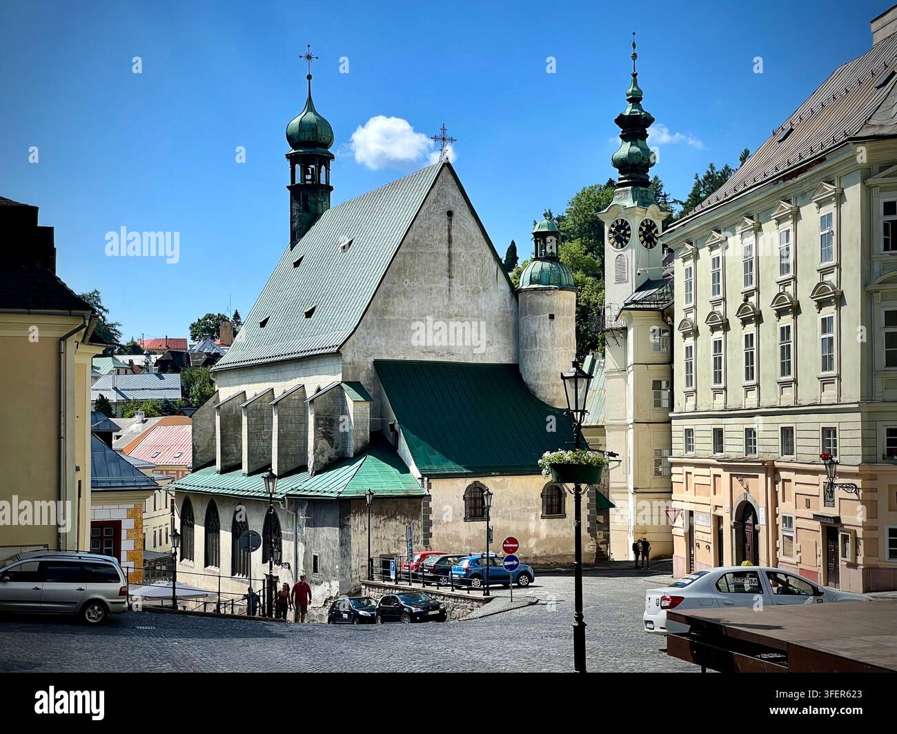 Foto orizzontale di Radničné námestie a Banská Štiavnica, Slovacchia, che mostra la chiesa gotica di Santa Elisabetta e la torre dell'orologio del Municipio - Immagine stock catturata con smartphone