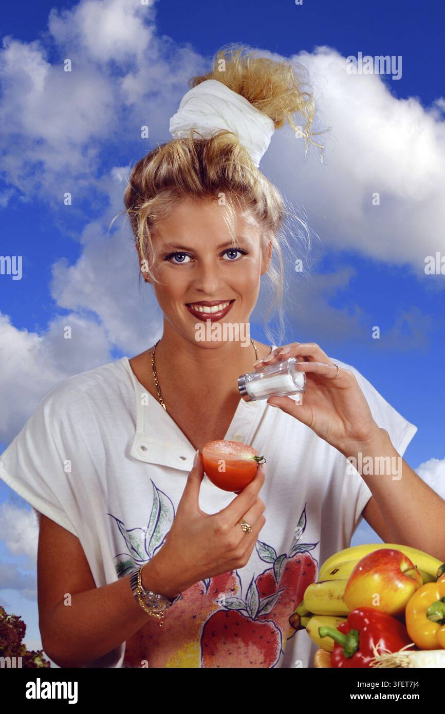Donna bionda che mangia un pomodoro con sale a colazione, 25 anni, bionda, bionda Foto Stock