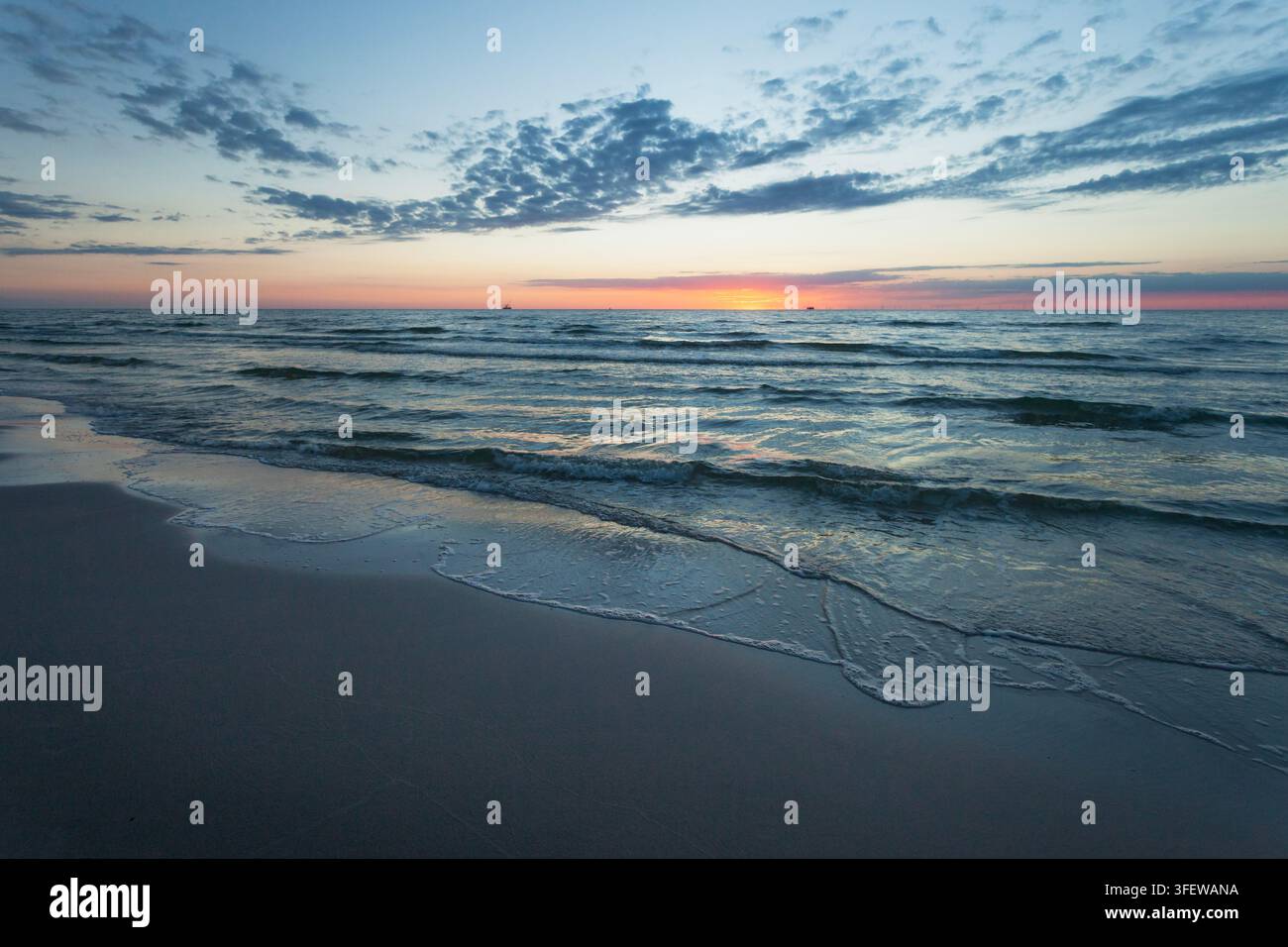 Onde calme del Mar Baltico e spiaggia al tramonto, vista estiva Foto Stock