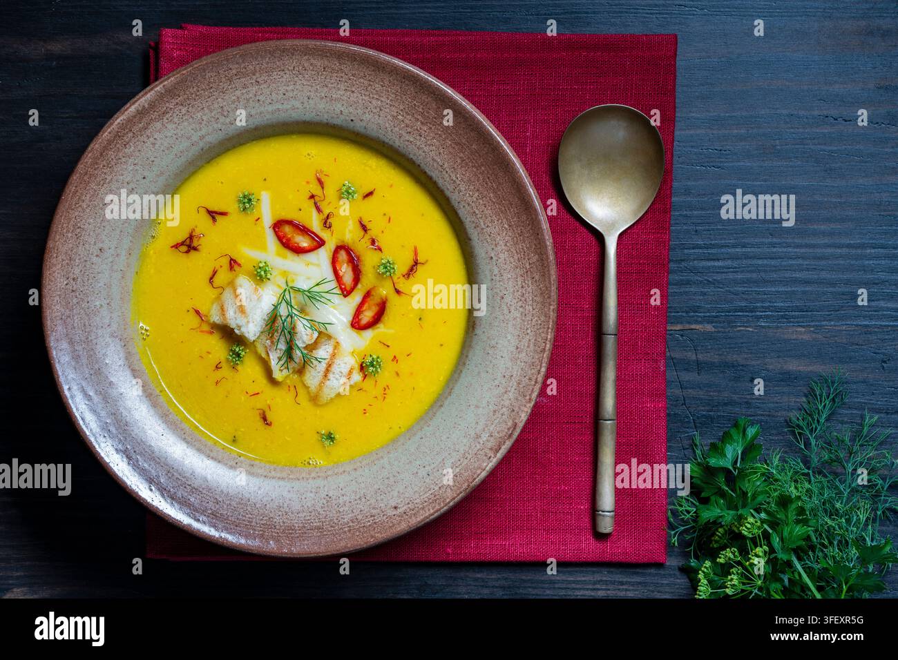 Zuppa cremosa gialla con crostini e peperoncino chili. Vista dall'alto di una zuppa cremosa gourmet di zucca o lenticchie gialla servita con crostini grigliati, peperoncino chili affettato Foto Stock
