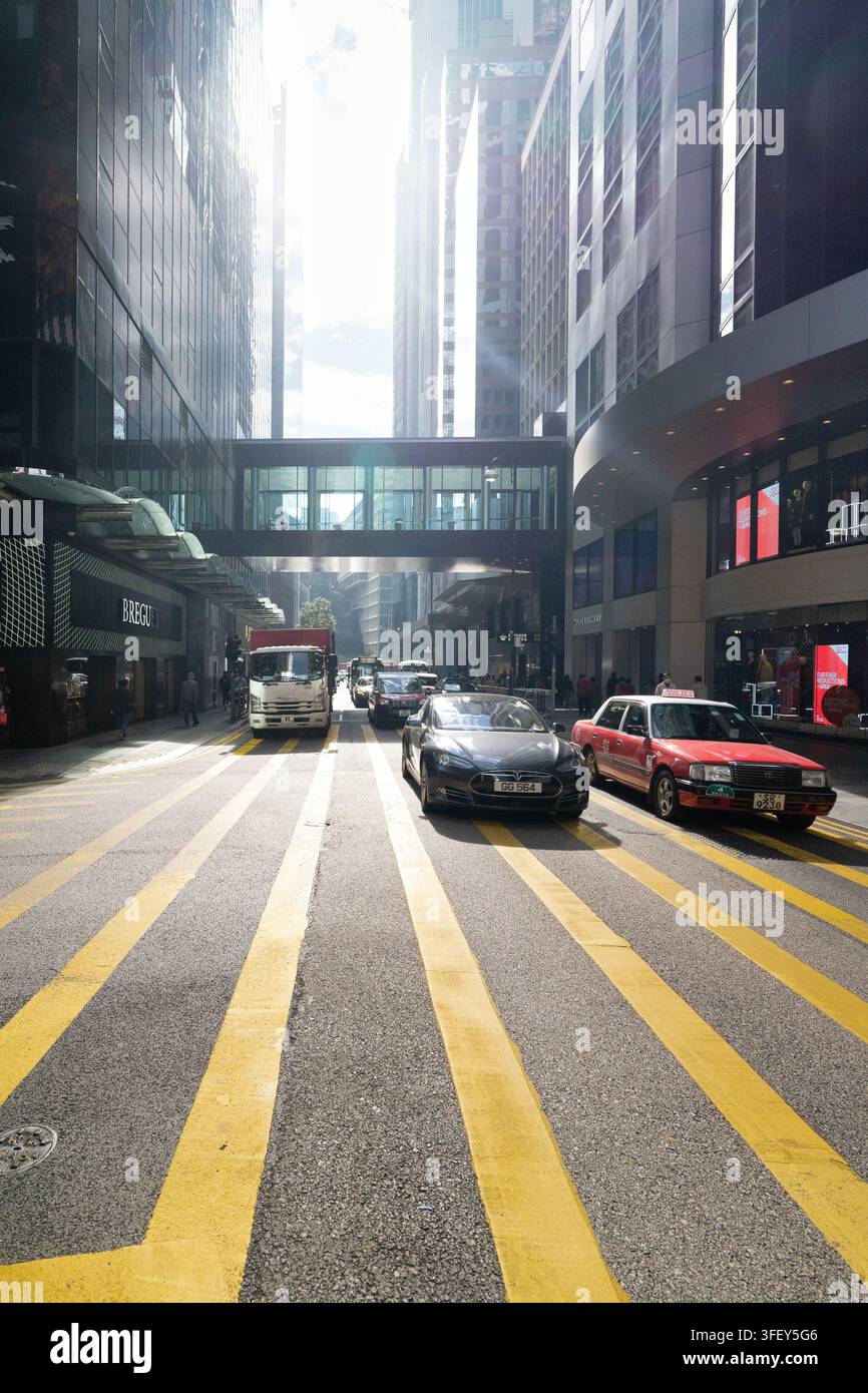 I veicoli riempiono Chater Road nel centro di Hong Kong, passando davanti al Prince's Building mentre i pendolari attraversano il vivace distretto finanziario e commerciale. Foto Stock
