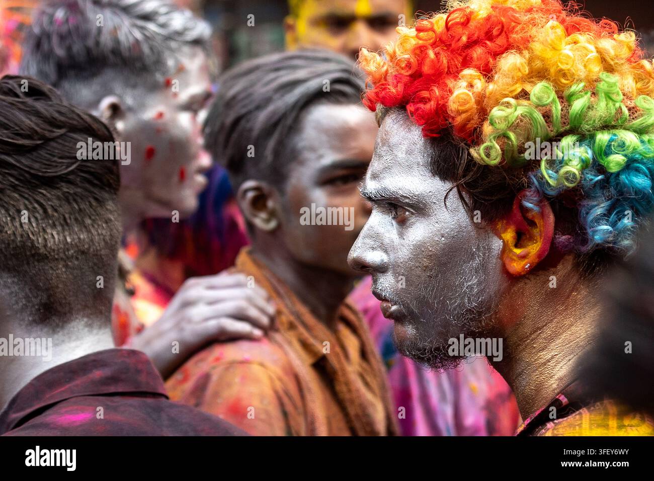Uomo con una parrucca colorata durante le celebrazioni di Holi a Varanasi, in India. Foto Stock