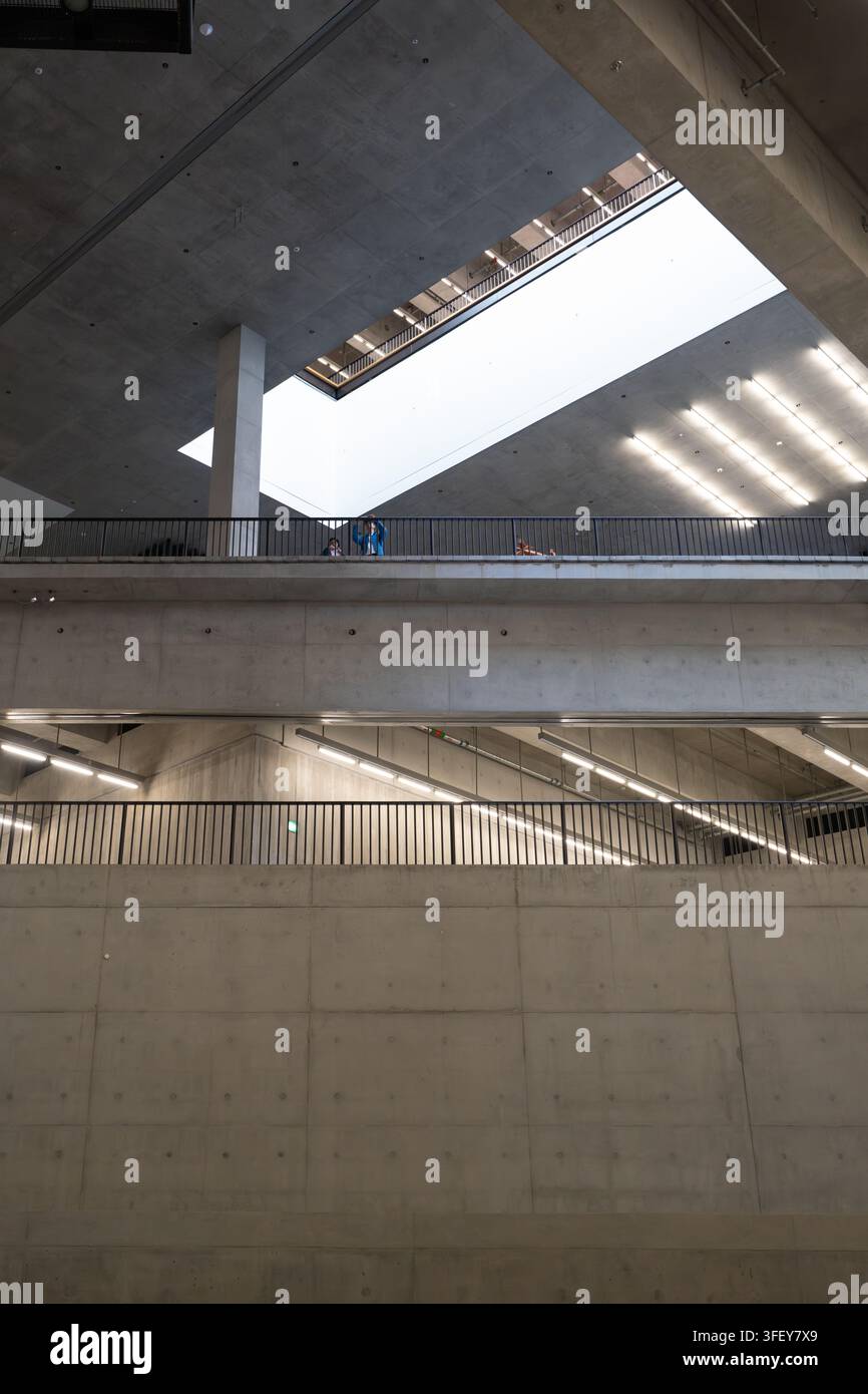 I visitatori esplorano la sorprendente architettura in cemento all'interno del museo M+ nel distretto culturale di West Kowloon a Hong Kong. Foto Stock
