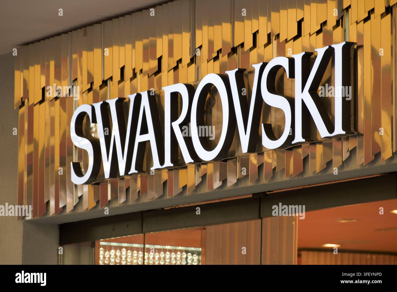 Lugano, Ticino, Svizzera – 19 agosto 2026: Insegna con logo Swarovski montata su una facciata specchiata dorata decorativa all'ingresso di una boutique di lusso. Concep Foto Stock