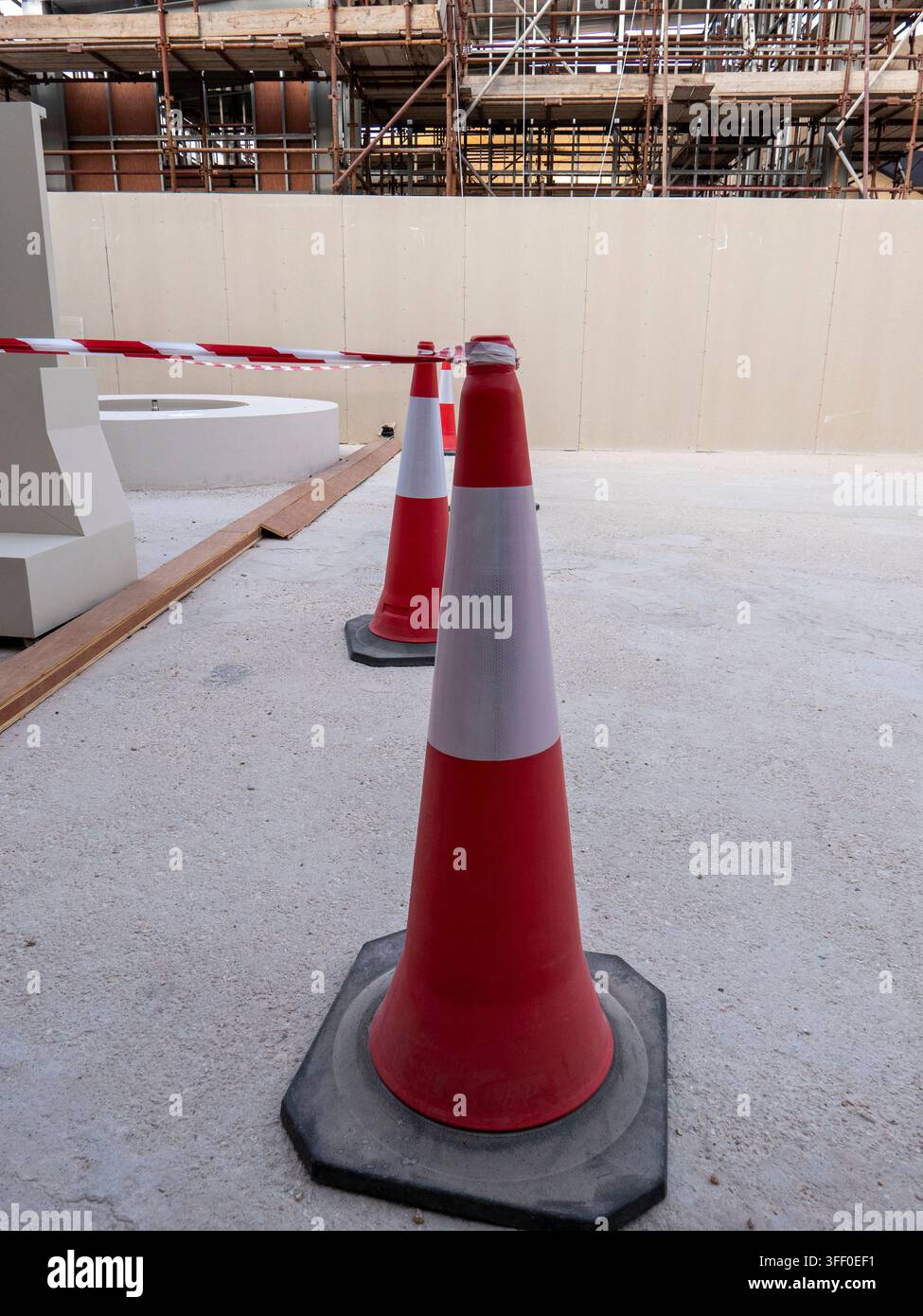 Coni di sicurezza stradale rossi e bianchi con nastro di barriera a strisce che bloccano un'area di cantiere all'aperto vicino ai terreni del museo. Foto Stock