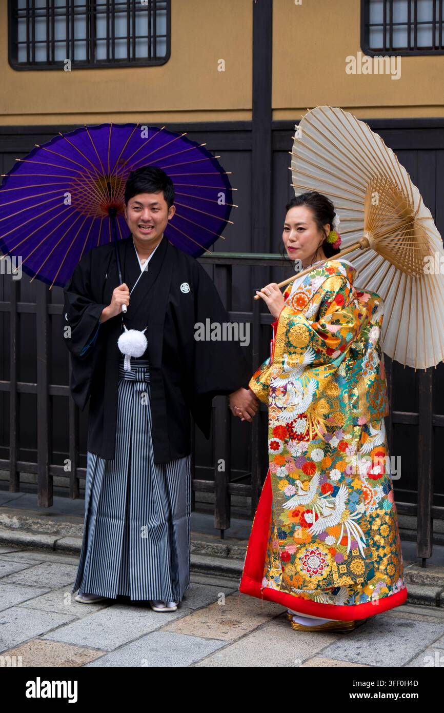 Coppia di sposi giapponesi appena sposati in tradizionali kimoni da matrimonio che posano con ombrelli bangasa su una strada a Higashiyama, Kyoto, Giappone. Foto Stock